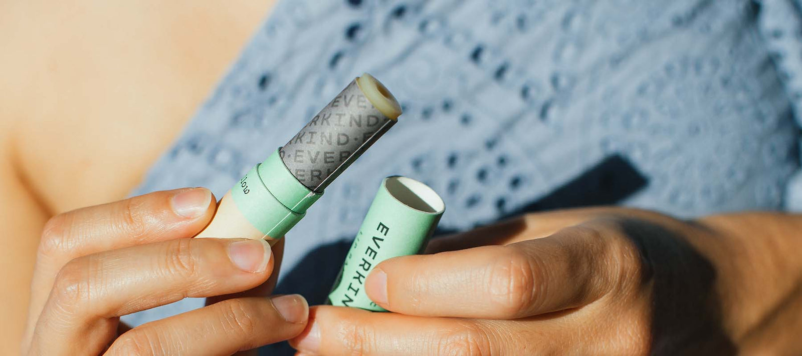 Person holding Everkind natural lip balm in compostable paper tube, ready to apply. Organic lip care made in New Zealand.