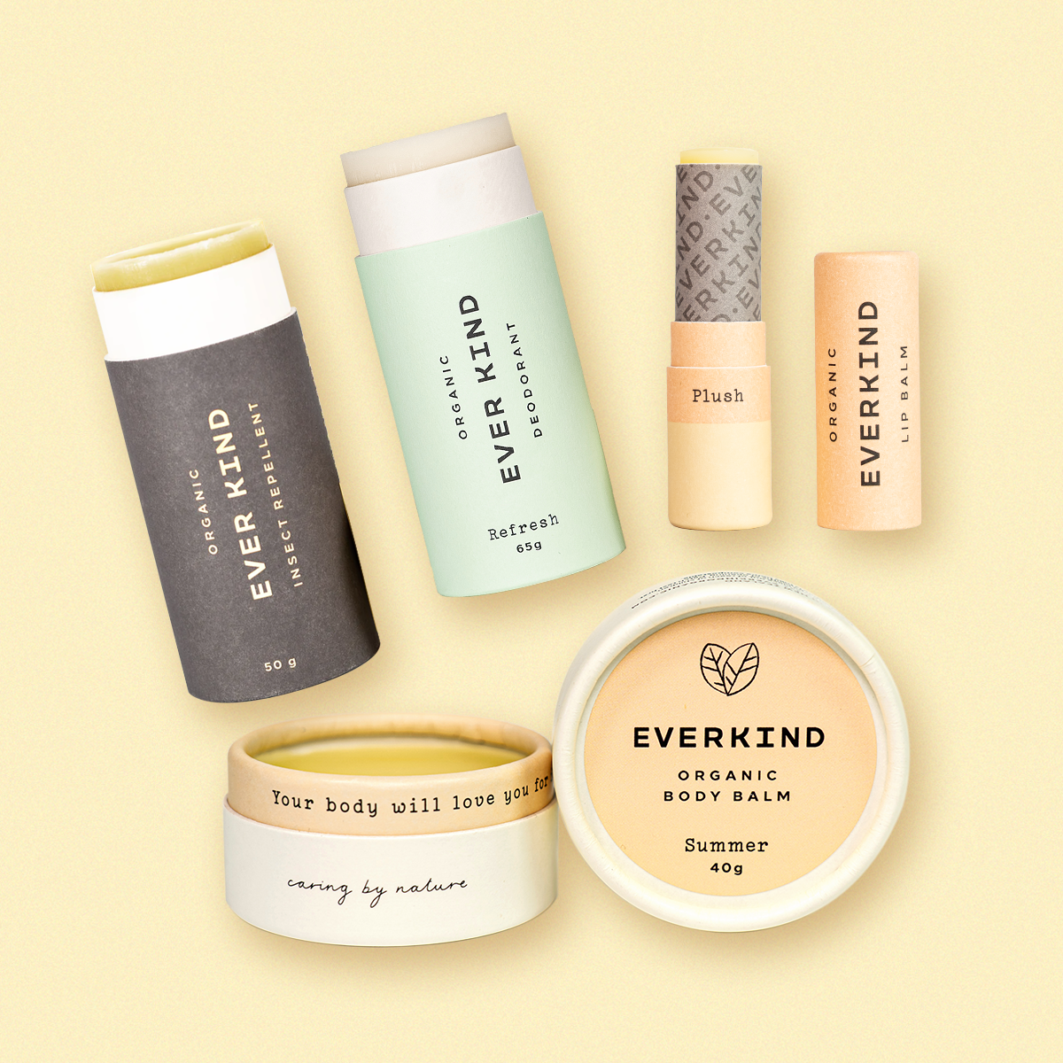 Flat lay of Everkind&#39;s All Set for Summer Bundle including deodorant, insect repellent, lip balm, and Summer body balm, all in compostable packaging on a warm yellow background.