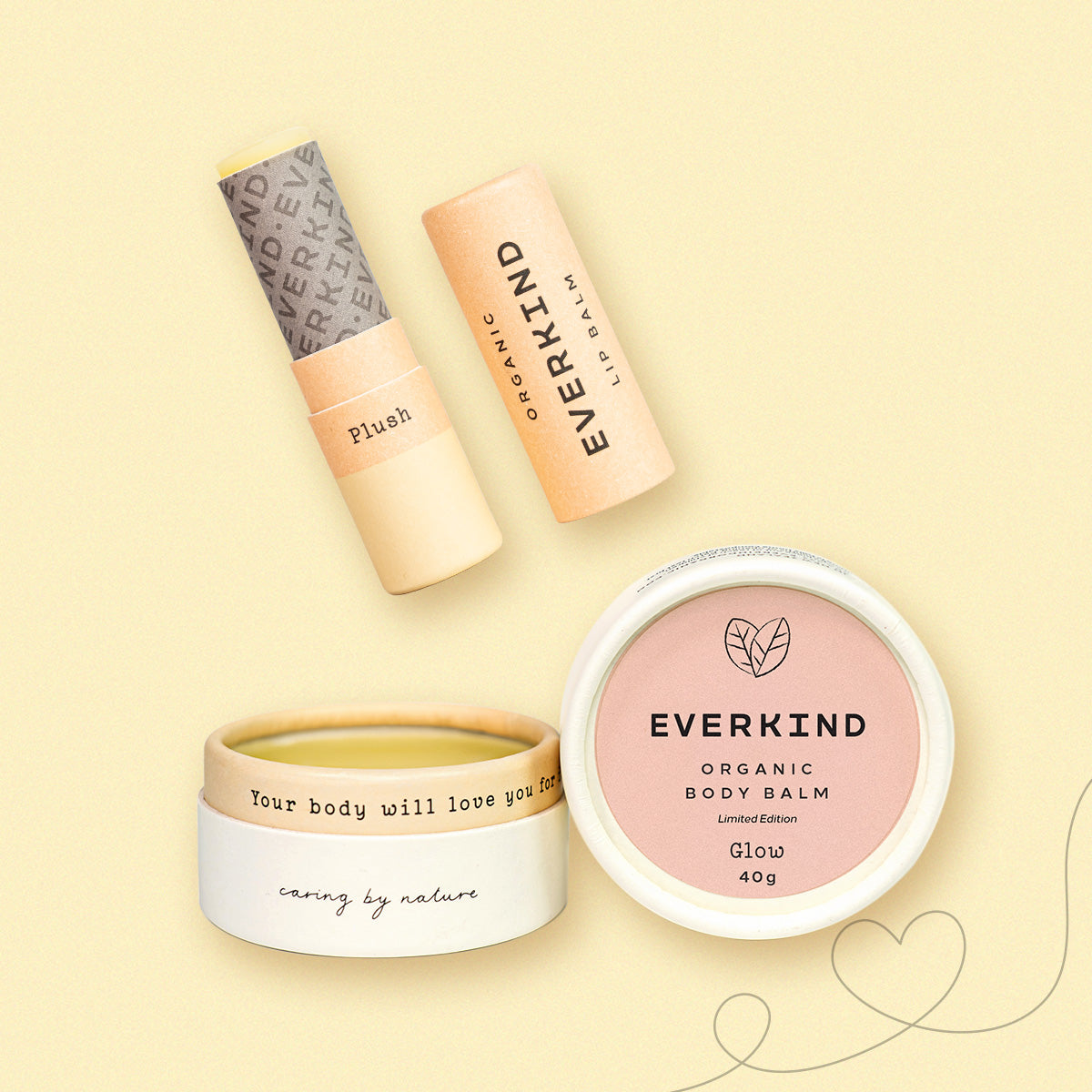 Flatlay of Everkind’s Glow Box featuring Glow body balm and Plush lip balm, surrounded by  heart illustrations on a soft yellow background.