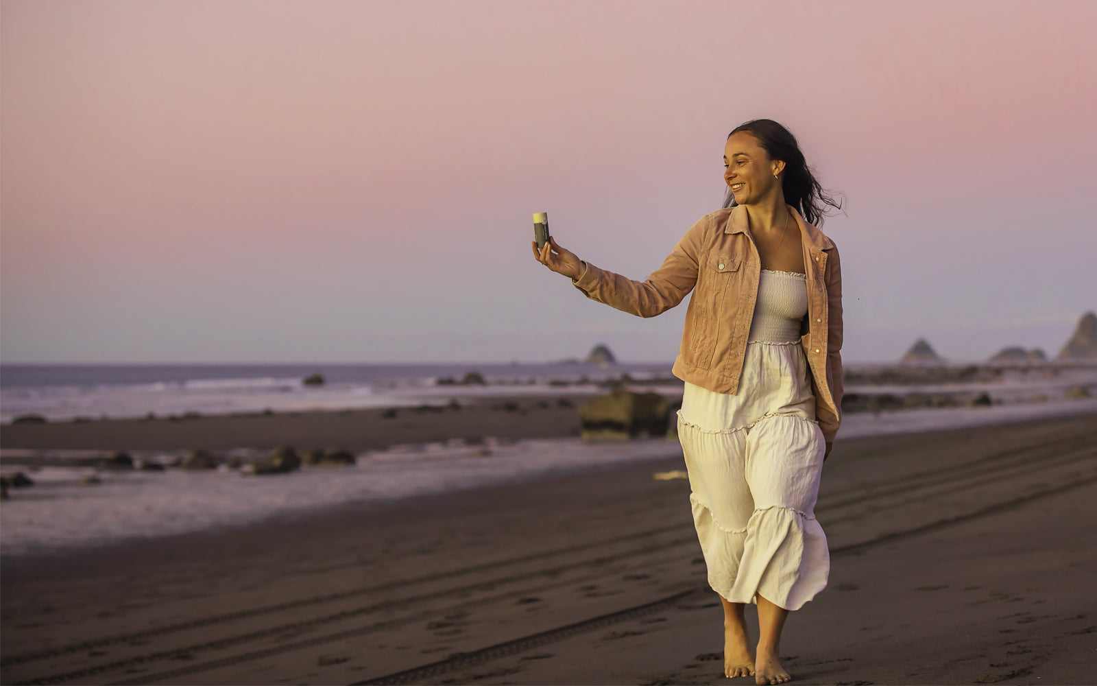 Woman on Taranaki beach with Everkind Organic Insect Repellent. Safe and effective, with a beautiful scent and a beautifully low environmental impact.
