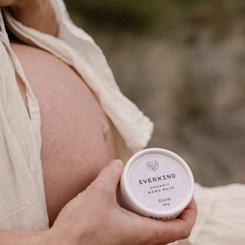 Photo of pregnant woman holding Everkind's Mama Balm Bloom. This is the only massage balm for mothers packaged in a purely paper jar. Bllom is scented with pure organic lavender, which is the most relaxing scent on earth.