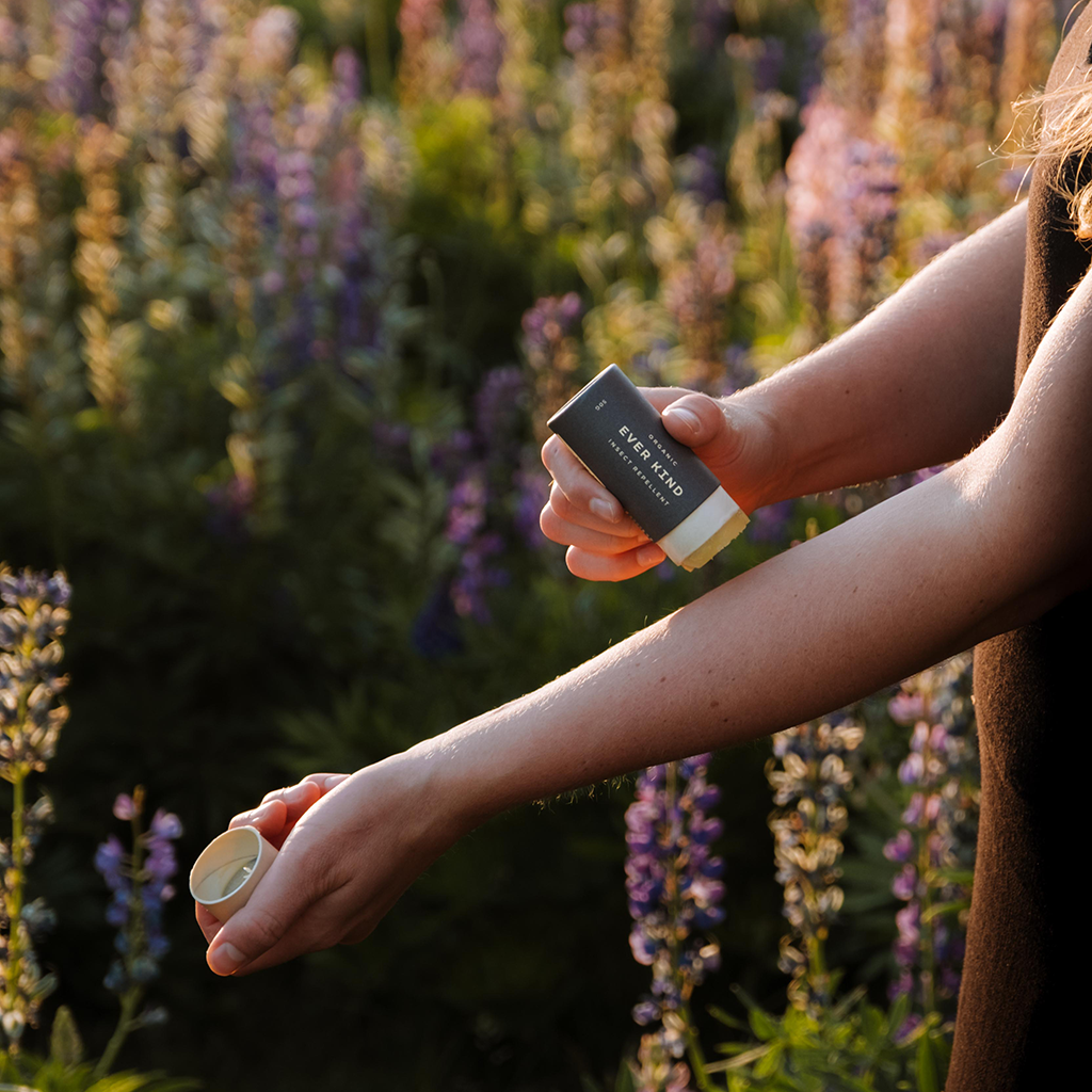 Woman applying Everkind Organic Natural Insect Repellent in the great outdoors. Perfect for eco-travel, this effective formula really works.