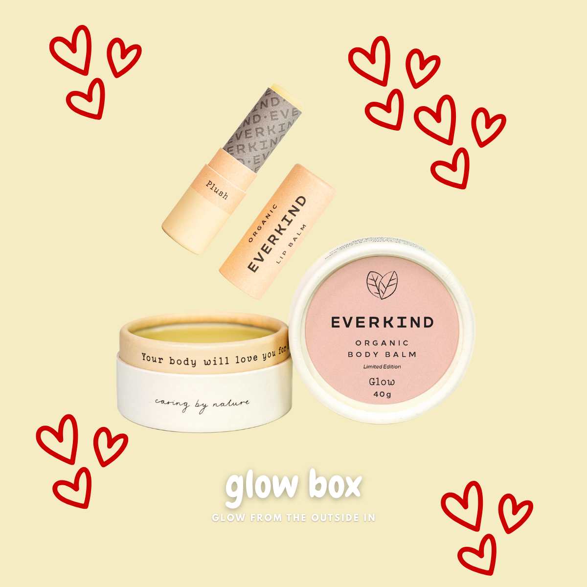 Flatlay of Everkind’s Glow Box featuring Glow body balm and Plush lip balm, surrounded by red heart illustrations and the text “Glow Box - Glow From the Outside In” on a soft yellow background.